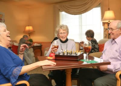Two women and a man playing chess and drinking ice tea